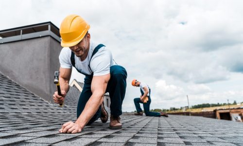 selective-focus-of-handyman-holding-hammer-while-repairing-roof-near-coworker.jpg